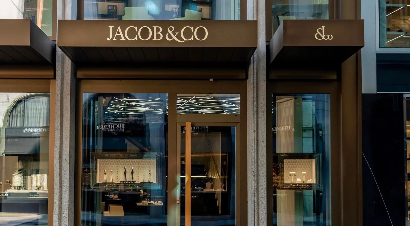 The JACOB & CO storefront, its name in gold above two lit window displays.
